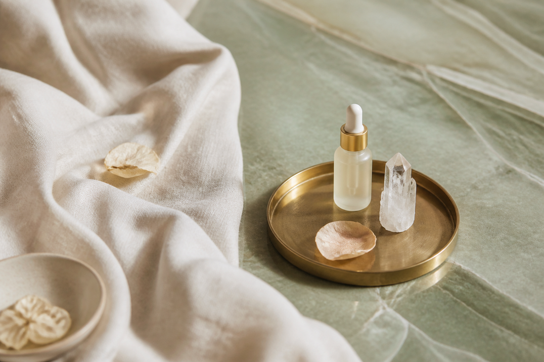 Dropper, quartz, and dried petals on a brass tray — curation as a standard